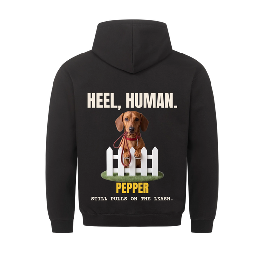 Heel, Human custom pet hoodie black, back print - your dog behind a picket fence with a red leash in its mouth, with name