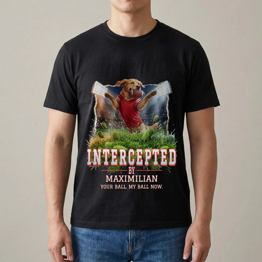 Man wearing a black T-shirt with a personalized print: golden retriever in a red jersey leaping under stadium floodlights with a football in its mouth, "Intercepted by Maximilian" and "Your ball. My ball now."